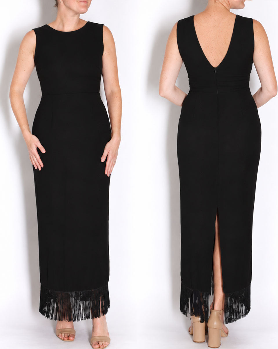 A sleeveless black maxi dress shown on a model from the front and back. The dress features a deep V-neckline on the back, a high slit, and a black fringe hem.