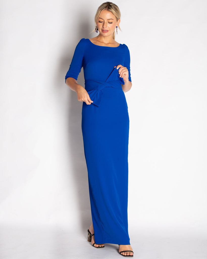 A Royal Blue floor length gown made in a stretch crepe material that is comfortable to wear. Elegant boat neck detail with 3/4 length sleeves. This dress waist line is at natural waist with a removable sash that can be styled with or without the gown.