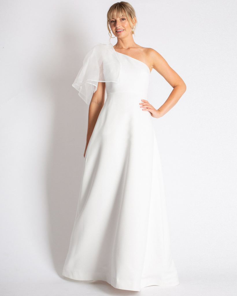 A combination of modern romantic & classic style in the Vivienne Gown. Asymmetrical, fit & flare silhouette with an effortless organza tie on the shoulder. Made in a structured material that drapes effortlessly. 